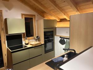 a kitchen with black appliances and wooden ceilings at Chalet La Tarine in Saint-Marcel