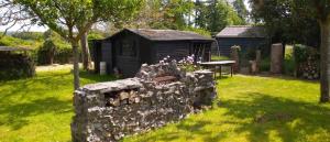 a stone wall in a yard with a shed at Ty Ar Bleiz Gwenn - La maison du Loup Blanc in Trégarvan