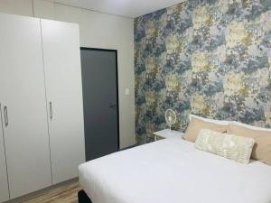 a bedroom with a white bed and a floral wallpaper at DMN City Merensky Apartment in Windhoek