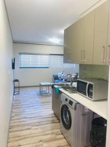 a kitchen with a washing machine and a microwave at DMN City Merensky Apartment in Windhoek