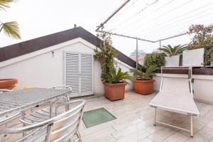 Monte Napoleone Split-level Terrace Apartment - Top Collection في ميلانو: شرفة مع طاولة وكراسي والنباتات