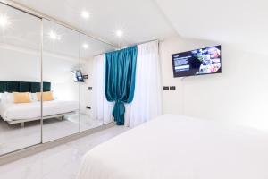 Schlafzimmer mit einem Bett, einem TV und einem Spiegel in der Unterkunft Monte Napoleone Split-level Terrace Apartment - Top Collection in Mailand