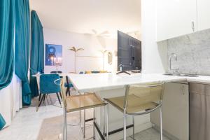 a kitchen with a white counter and chairs at Monte Napoleone Split-level Terrace Apartment - Top Collection in Milan