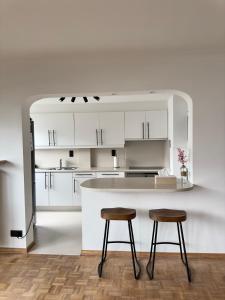 a kitchen with white cabinets and two bar stools at Cosy apartment in Ghent in Ghent