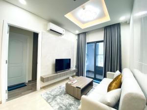 a living room with a white couch and a tv at Monarchy Apartment in Da Nang