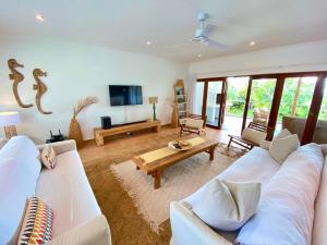 a living room with a white couch and a tv at Woodlands Beach Villa in Southbroom