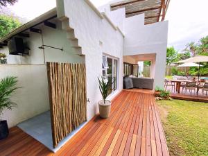 a house with a wooden deck with a patio at Woodlands Beach Villa in Southbroom