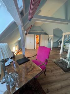 Cette chambre comprend une table et une chaise rose. dans l'établissement Hotel Stadtresidenz, à Hildesheim