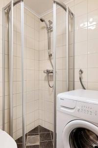a washing machine in a bathroom with a shower at Fresh studio apartment, a short walk from Bryggen in Bergen