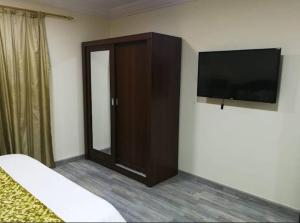 a bedroom with a flat screen tv and a cabinet at بوابة الريادة in Ar Riḩāb
