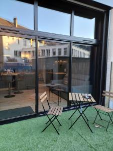 2 chaises et une table sur une terrasse avec fenêtres dans l'établissement Ô Valvi : loft avec balnéo, terrasse et parking, à Saint Lo