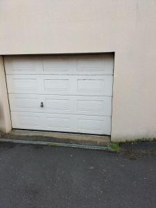 uma porta de garagem branca do lado de um edifício em Sous le pommier em Douvres-la-Délivrande