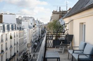 uma varanda com cadeiras e vista para a cidade em Hotel Royal Saint Honore Paris Louvre em Paris