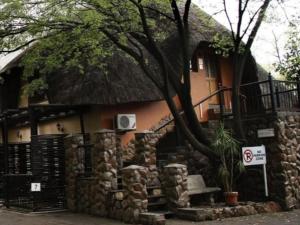 a house with a thatch roof and a stone wall at Lapalosa Lodge in Centurion