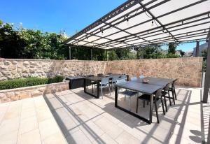 patio ze stołami i krzesłami pod pergolą w obiekcie Apartments Villa Lukas w mieście Cavtat