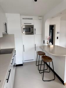 a white kitchen with two stools and a counter at Cosy apartment in Ghent in Ghent