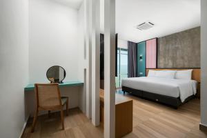 a bedroom with a bed and a desk with a chair at The Bayou Hotel Langkawi in Pantai Cenang