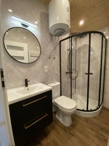 a bathroom with a shower and a toilet and a sink at Wypoczynkowo Domki Letniskowe in Mikołajki