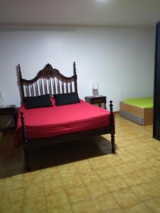 a bedroom with a wooden bed with a red blanket at Moradia Lili in Ronqueira