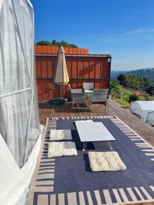 a patio with a table and chairs and an umbrella at Green bus view inside hills khaokho in Khao Kho