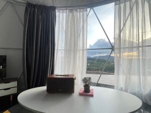 Green bus view inside hills khaokho في كاو كو: طاولة عليها جهاز كمبيوتر محمول أمام النافذة