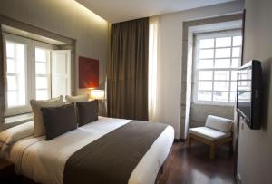 a hotel room with a large bed and a chair at Hotel Carris Porto Ribeira in Porto