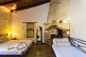 a bedroom with two beds and a stone fireplace at Allaria villa in Margarítai