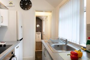 a kitchen with a sink and a clock on the wall at OnPoint - Spacious 4 Bed House in Hanley