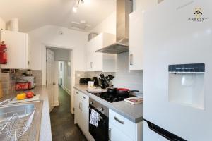 een keuken met witte kasten en een fornuis met oven bij OnPoint - Spacious 4 Bed House in Hanley