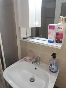 ein Waschbecken mit einer Flasche Seife und einem Spiegel in der Unterkunft warm home in Koropi