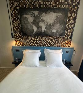 a bed with two white pillows and a map on the wall at Logis Au Vieux Morvan "fait peau neuve" in Château-Chinon