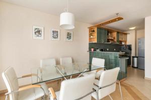 una sala da pranzo con tavolo in vetro e sedie bianche di 2BDR Duplex Apartment with Parking a Sofia