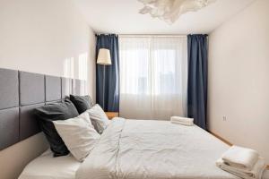 een slaapkamer met een groot wit bed en blauwe gordijnen bij 2BDR Duplex Apartment with Parking in Sofia
