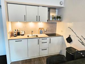 a kitchen with white cabinets and a sink at Borndiep Amelander Kaap 34 in Hollum