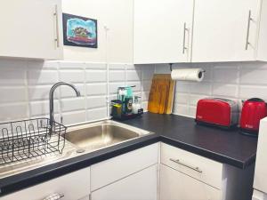 a kitchen counter with a sink and a red appliance at Apartment in Epsom With Free Parking in Epsom