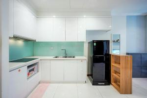 a kitchen with white cabinets and a black refrigerator at Raddison Luxury Apart - Vinhome Central Park, Landmark 81 Area and Great Park in Ho Chi Minh City
