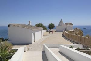 uma passagem que leva ao oceano com edifícios brancos em Casa Morango - Senhora da Rocha, Algarve em Porches