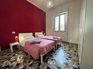 1 dormitorio con 2 camas y pared roja en Casina Emma by Nicola Real Estate, en Viareggio