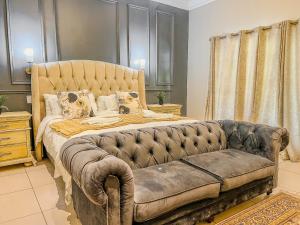 a bedroom with a large bed with a leather couch at The Lux Guesthouse in Kroonstad