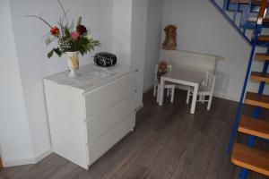 a white dresser with a vase of flowers on it at Ferienwohnung-Herbolzheim in Herbolzheim