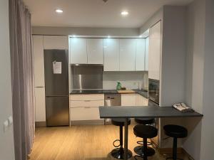 a kitchen with white cabinets and a table and stools at CALLE MARINA in Huelva