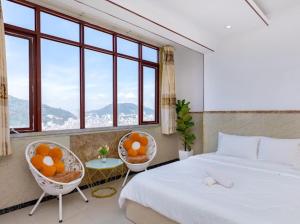 a bedroom with a bed and two chairs and windows at Khách sạn sơn thinh 23d Thuỳ Vân in Vung Tau