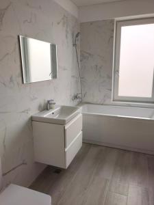 un bagno bianco con lavandino, vasca e finestra di Summer Smile by Euxin Accomodations a Năvodari Altre 11 foto