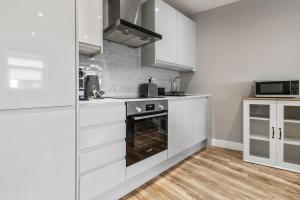 a kitchen with white cabinets and a stove at 2 Bedroom Flat, Wembley Stadium in London