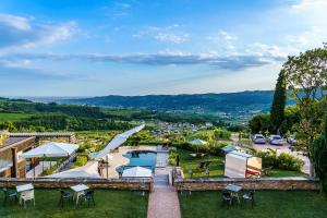 widok na ośrodek z basenem, stołami i parasolami w obiekcie Villa Balis Crema Verona Hills w mieście Grezzana