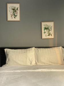 - un lit avec des draps blancs et 2 photos sur le mur dans l'établissement Grand Bangsaen Hotel, à Bang Saen
