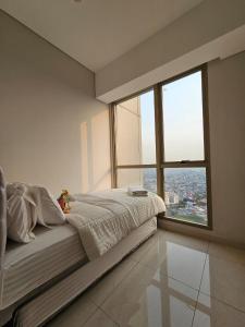 um quarto com uma cama grande e uma janela grande em 3BR Flat in Taman Anggrek Residence em Jacarta