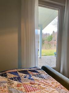 - une chambre avec une couette sur un lit à côté d'une fenêtre dans l'établissement Haus am See mit fantastischem Blick, à Rheinböllen