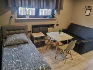 ein Schlafzimmer mit einem Bett, einem Tisch und einem Sofa in der Unterkunft Przystań in Rozalin