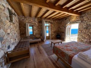 - une chambre avec un lit et un mur en pierre dans l'établissement Phisis Nature Retreat, à Donoussa